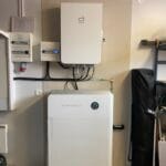Batterilager installerat i garage med väggmonterad växelriktare och energimätare.